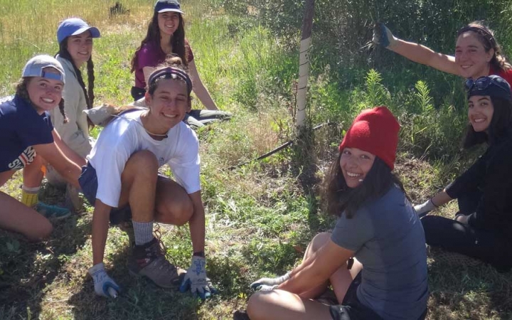 A group of people who appear to be doing trail work stop to smile at the camera.